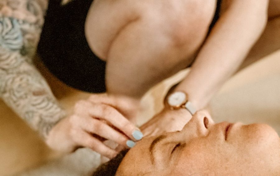 A woman with a tattoo gently touching another woman's forehead. Mornington Chinese Medicine